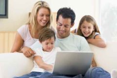 Family in living room with laptop smiling