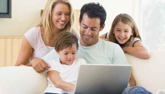 Family in living room with laptop smiling